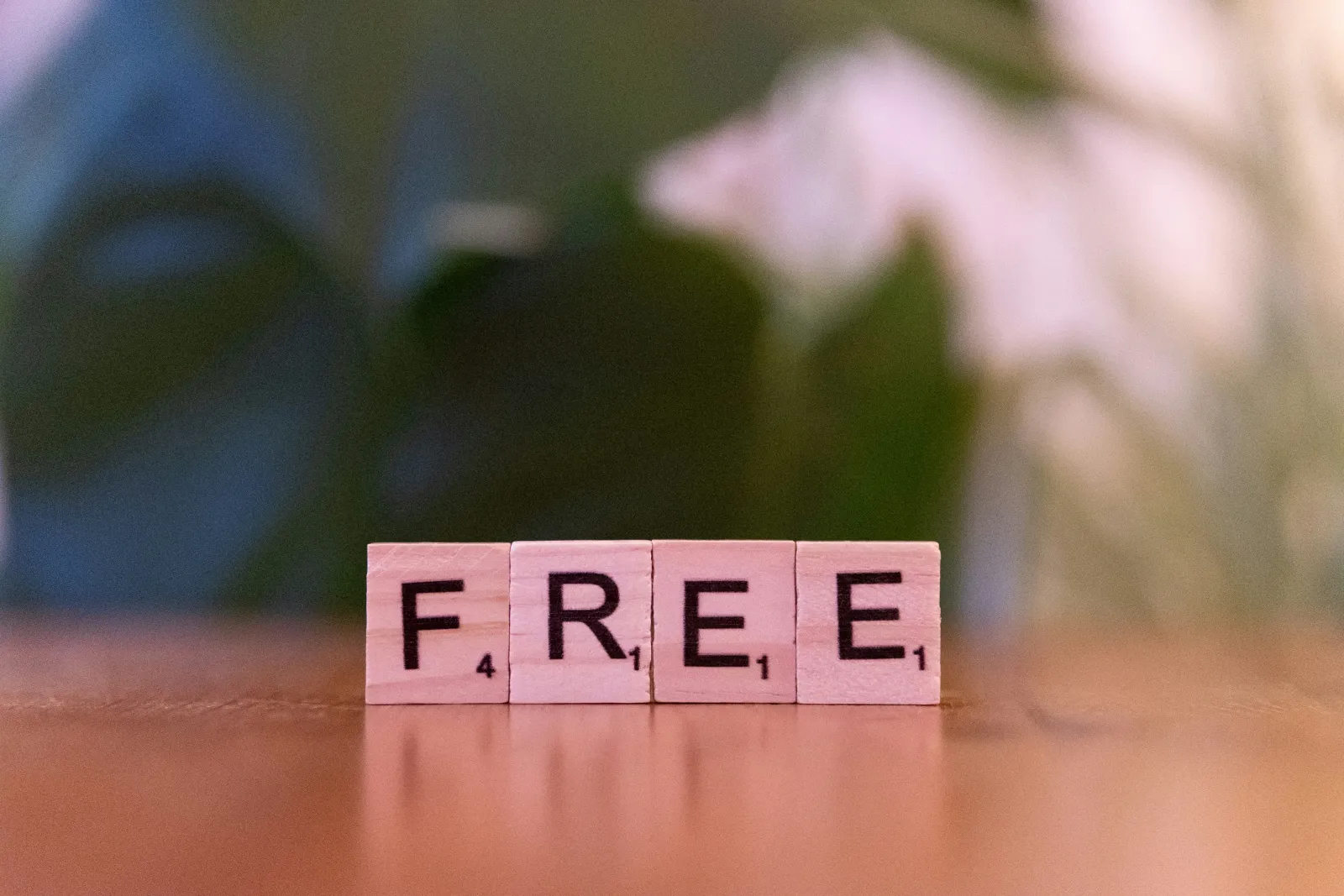 Wooden Scrabble tiles on a table spelling the word FREE: something useful that costs nothing extra.