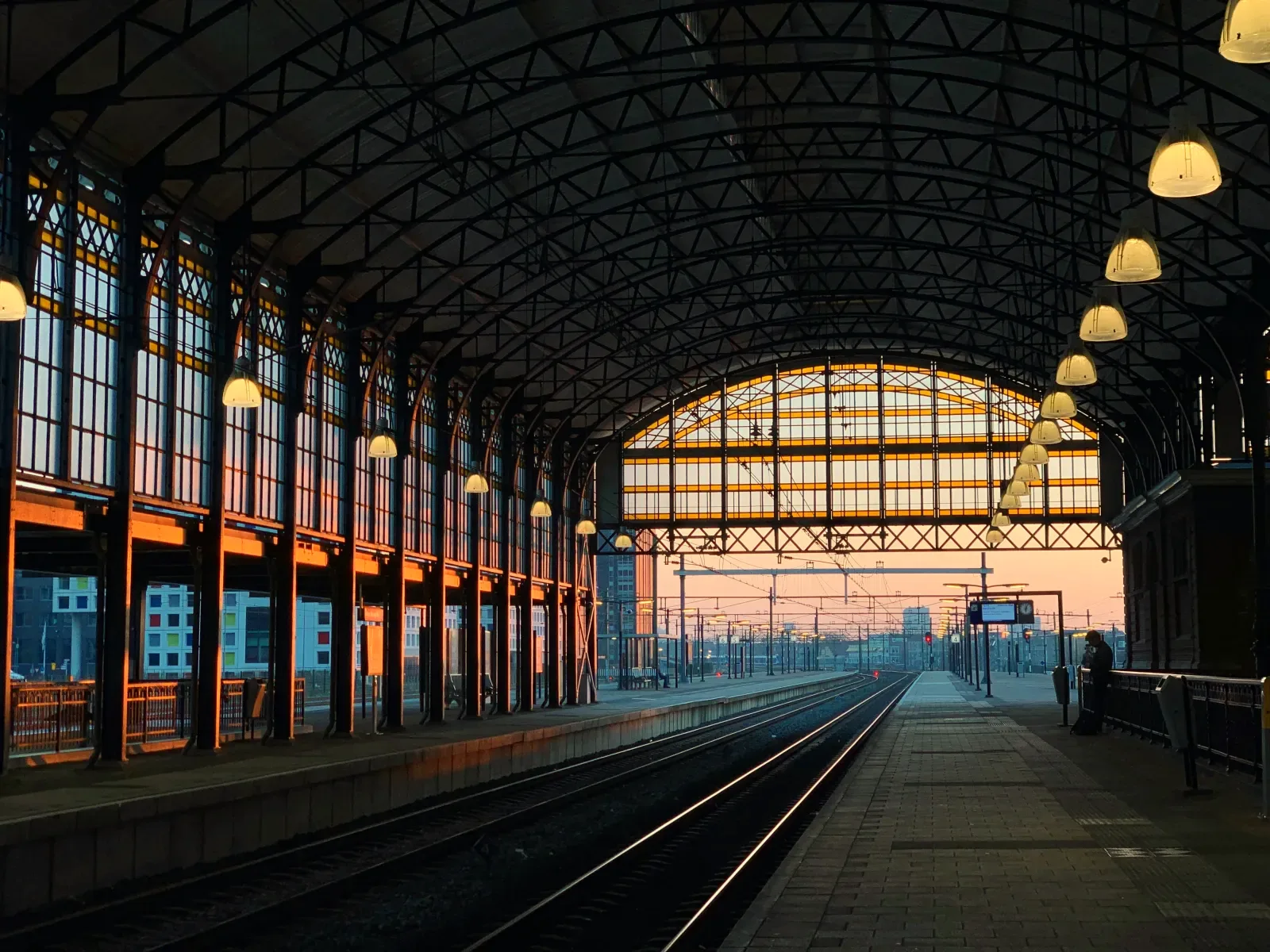 Empty station hall at dawn, tracks running out toward the horizon: by the time the train leaves, every switch that matters has already been set.
