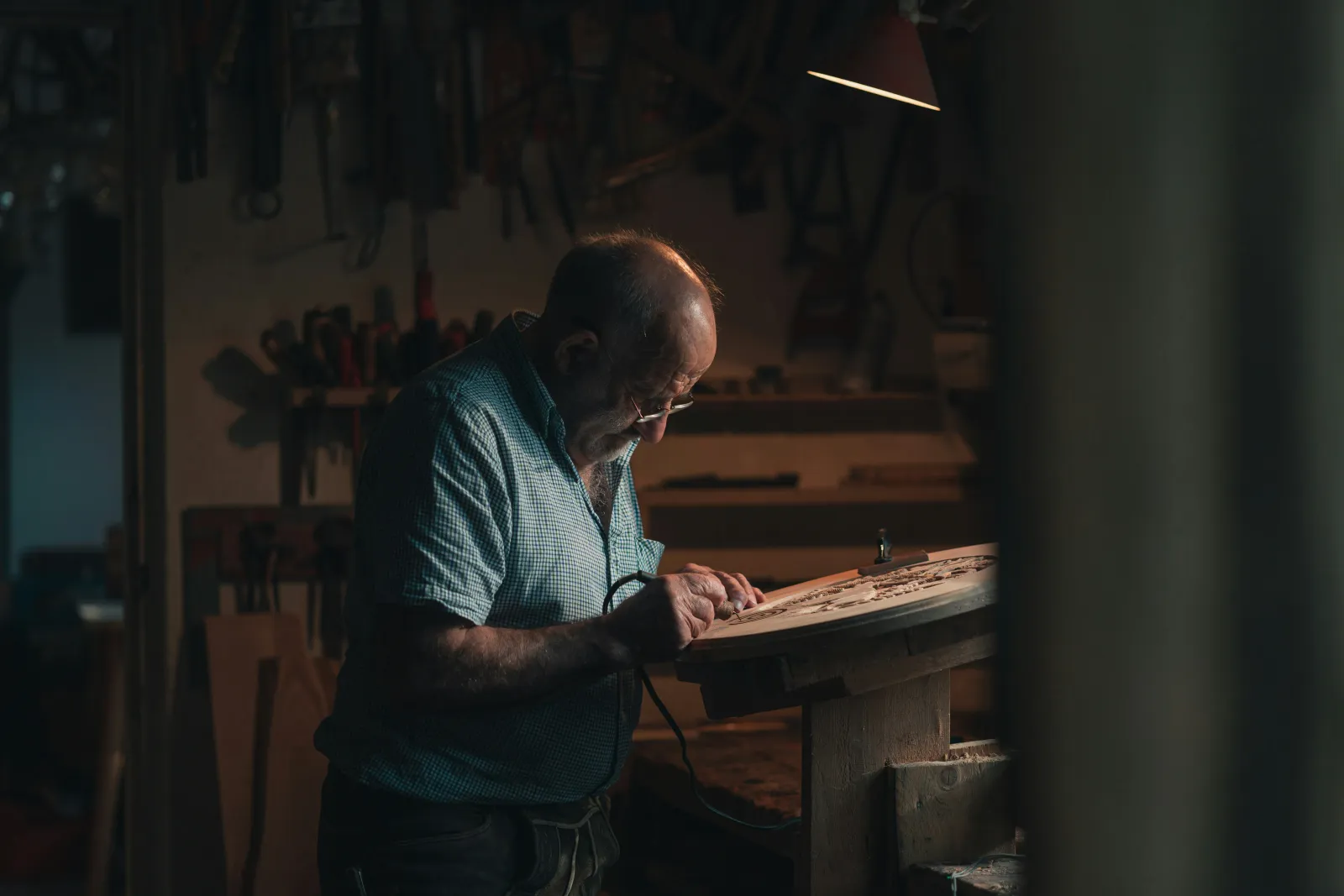 Craftsman doing detailed woodwork at a workshop bench